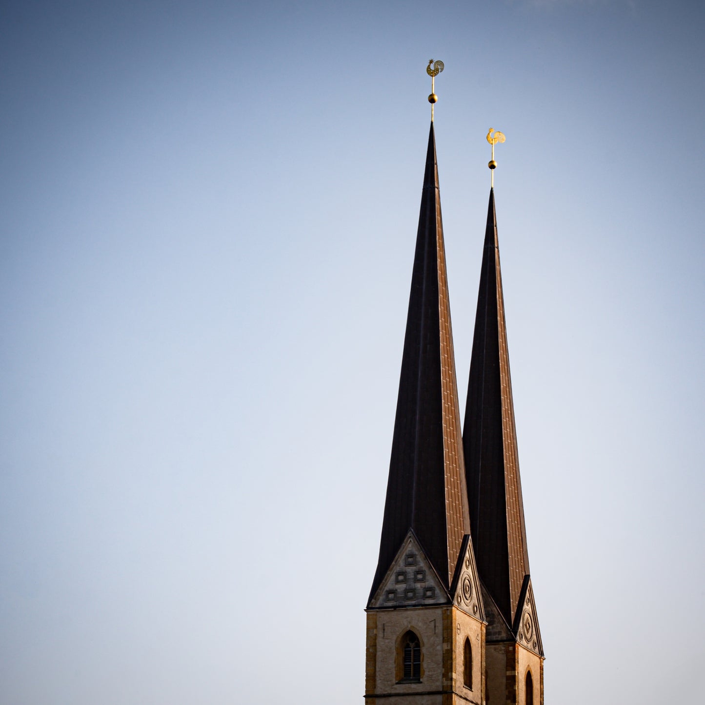 Zwei kupferne Kirchturmspitzen mit goldenen Wetterhähnen