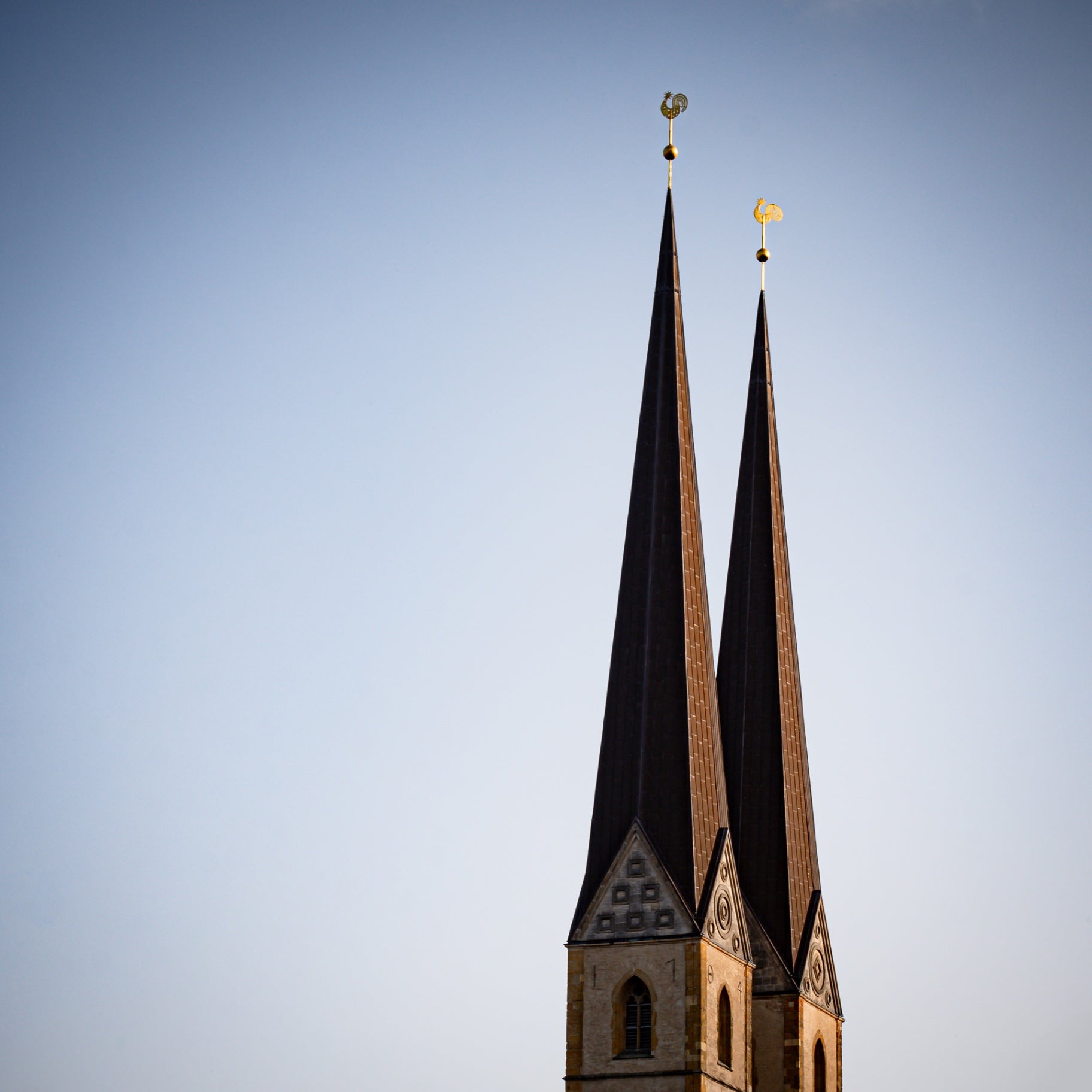 Zwei kupferne Kirchturmspitzen mit goldenen Wetterhähnen