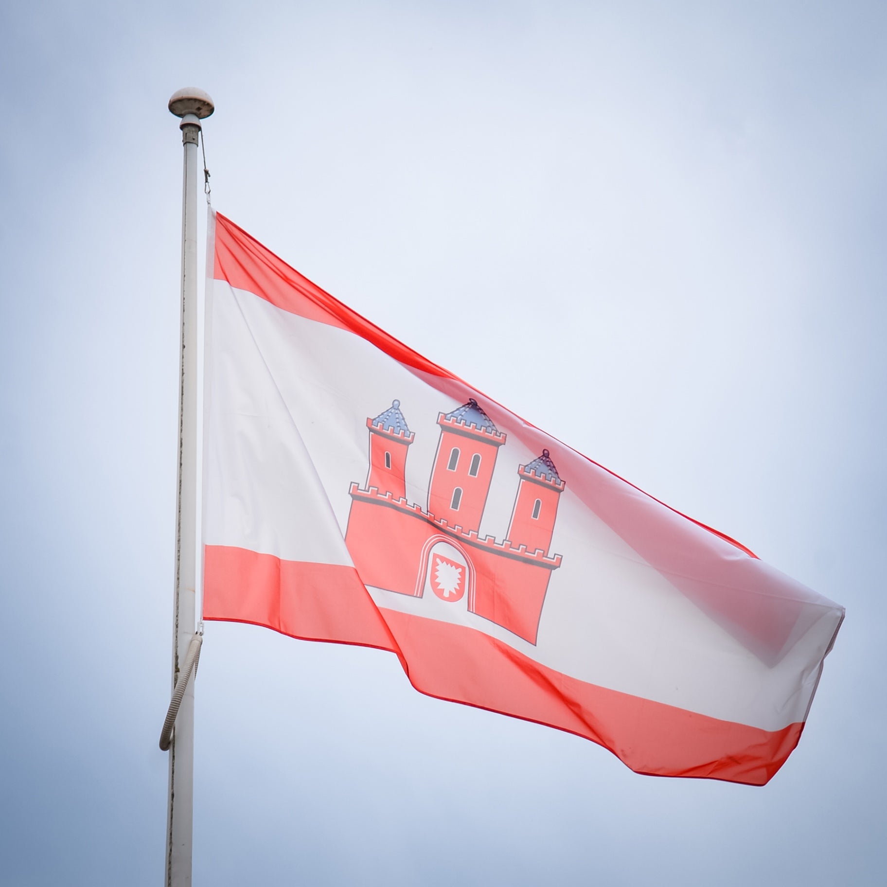 Rot-weiße Rendsburger Flagge mit Stadtwappen weht im Wind